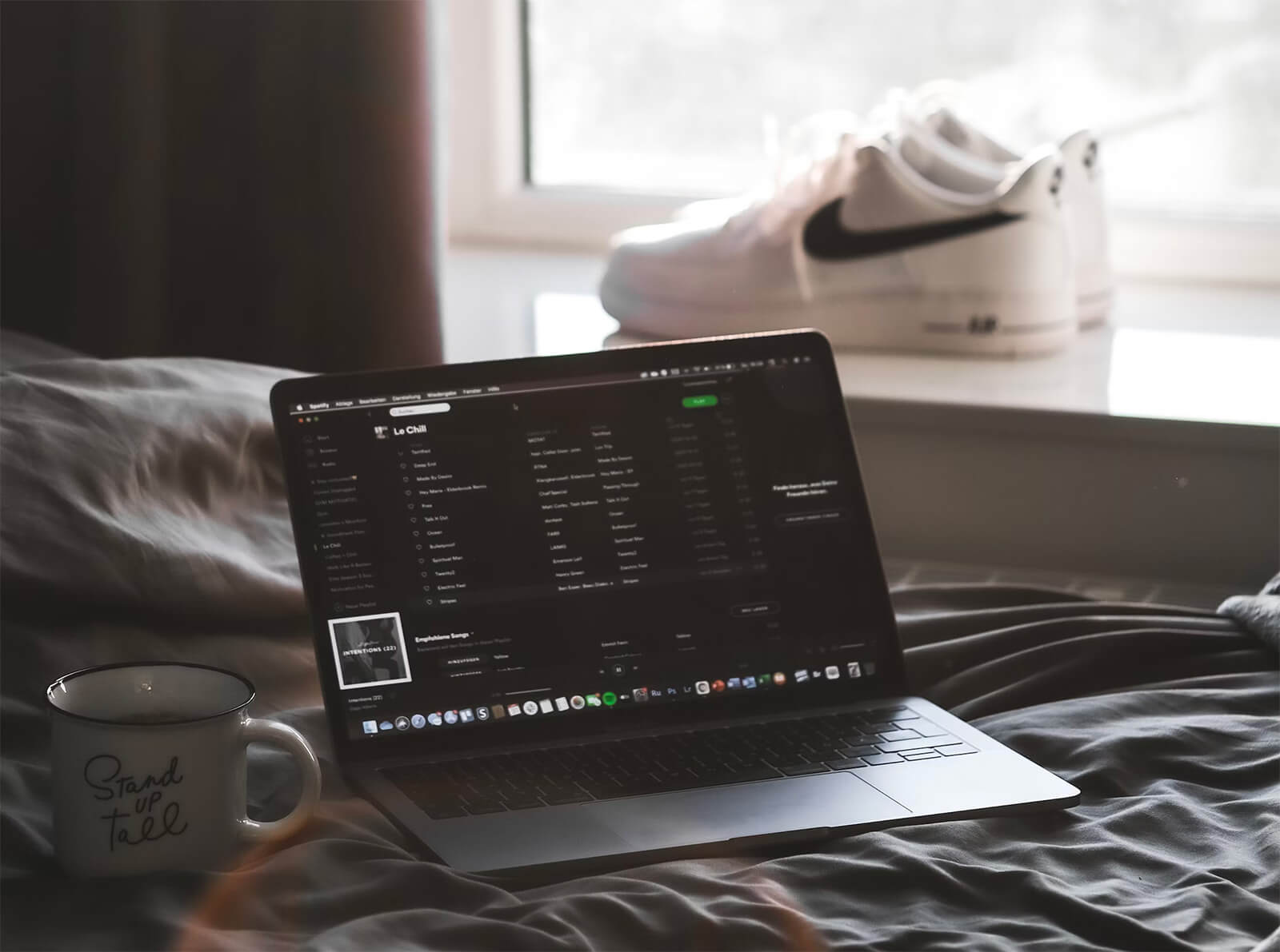 A laptop showing code beside a sketchbook and a cup of coffee