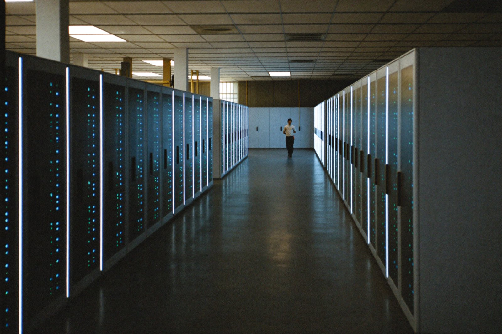 A lone technician walking a long aisle of server racks